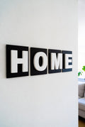 Two-colour shadow letters spelling HOME on a living room wall