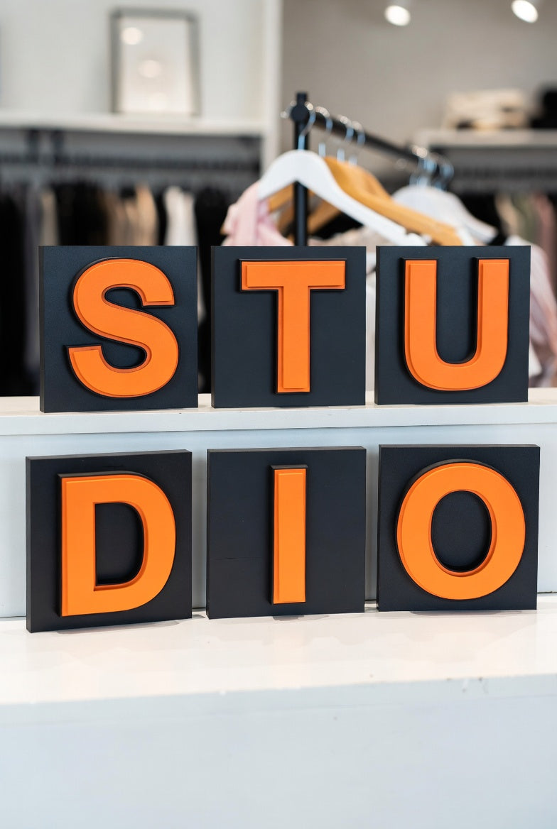 Orange shadow letters spelling STUDIO in a clothing store