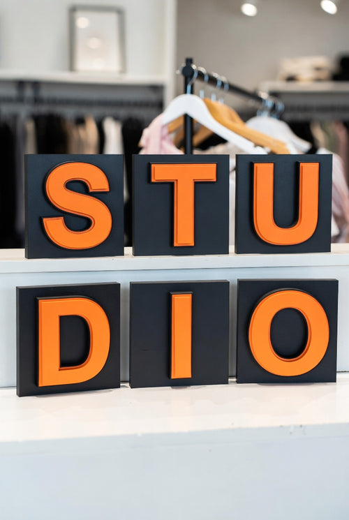 Orange shadow letters spelling STUDIO in a clothing store