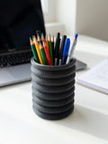 Charcoal grey Knit Stack pencil holder with pens on a desk beside a laptop