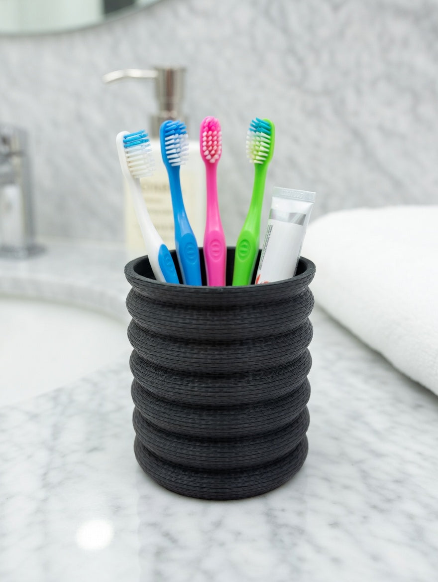 Charcoal grey Knit Stack pencil holder on a wooden desk with a plant