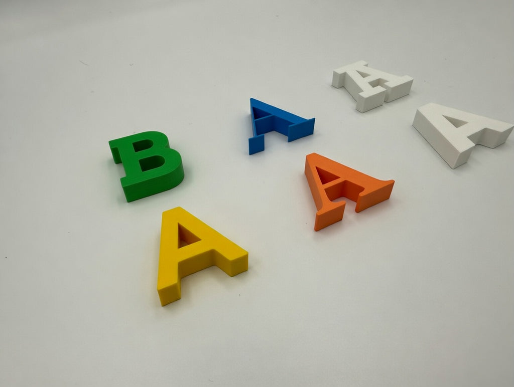 Mixed 3D printed letters in assorted colours, angled view