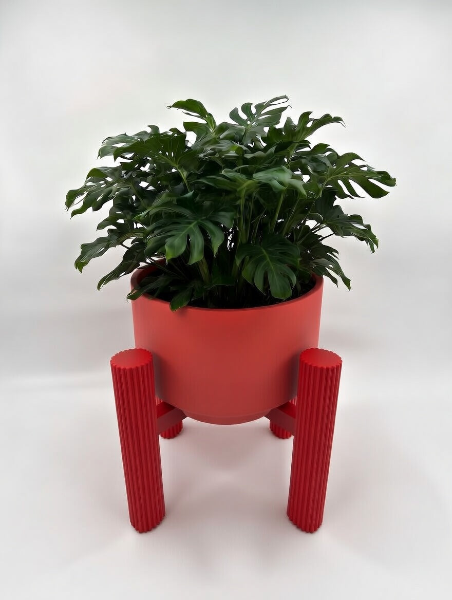 Red round fluted elevated plant stand with monstera, front view