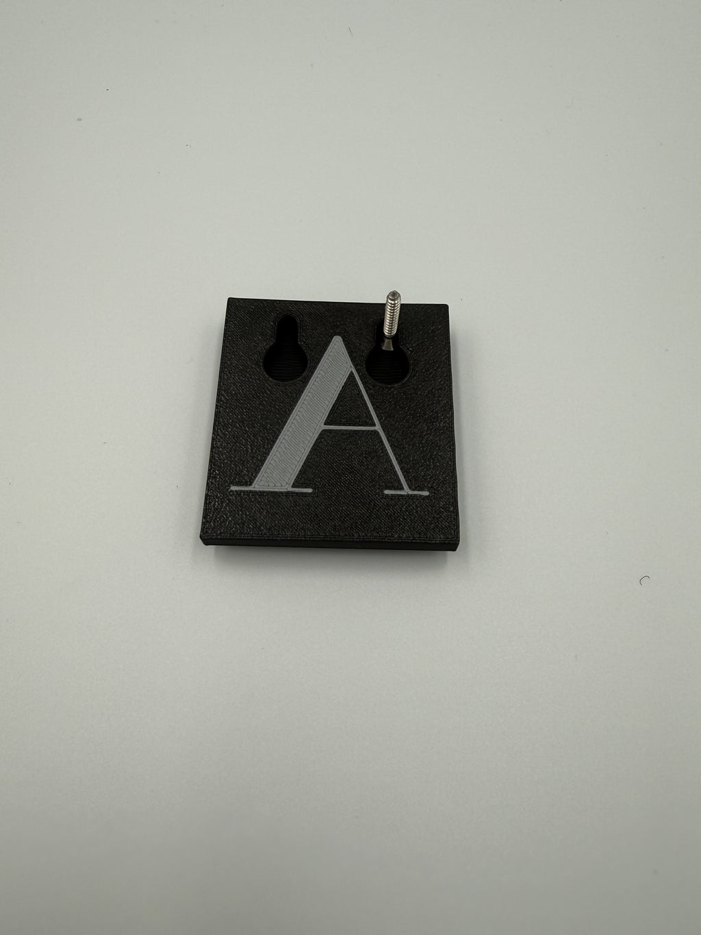 Back of a shadow letter showing the built-in keyhole slot on a screw