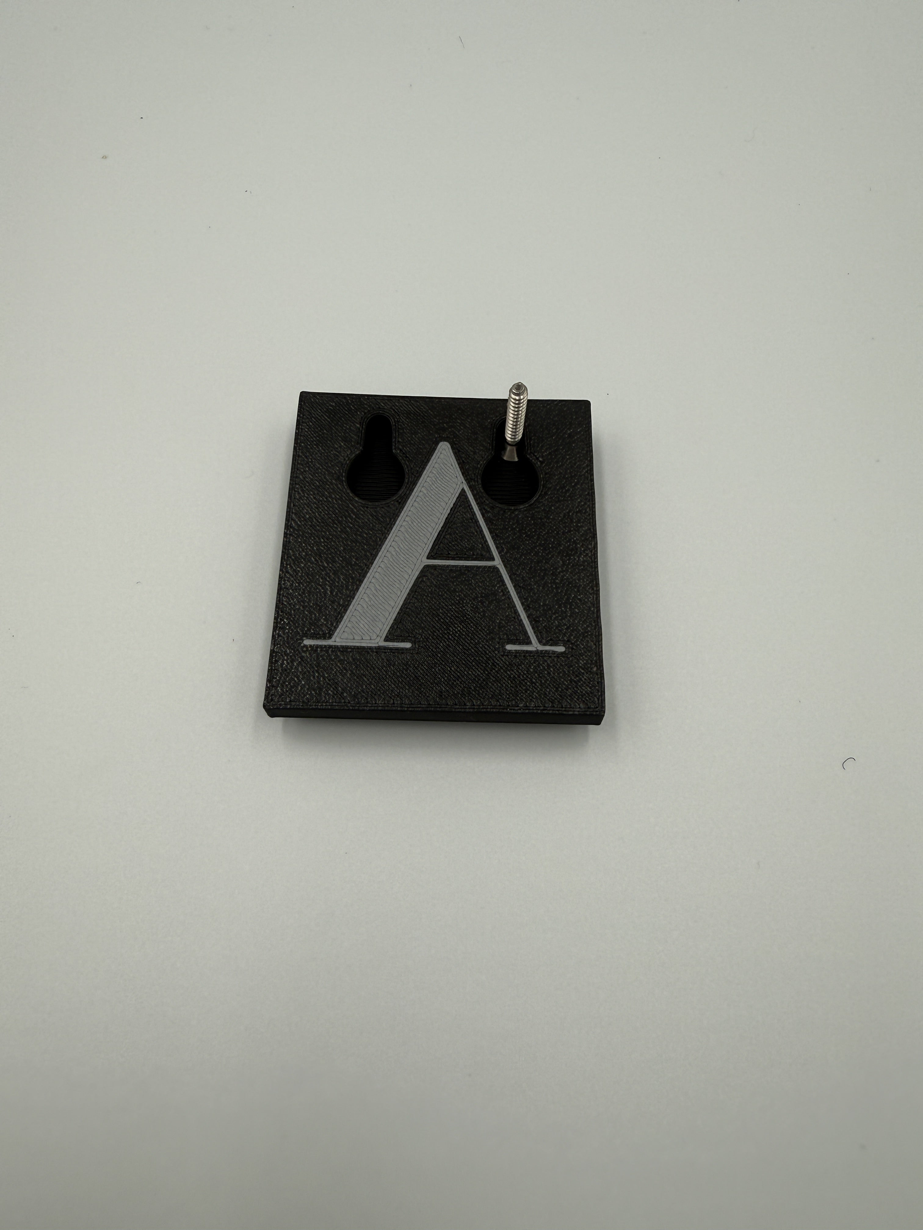 Back of a shadow letter showing the built-in keyhole slot on a screw