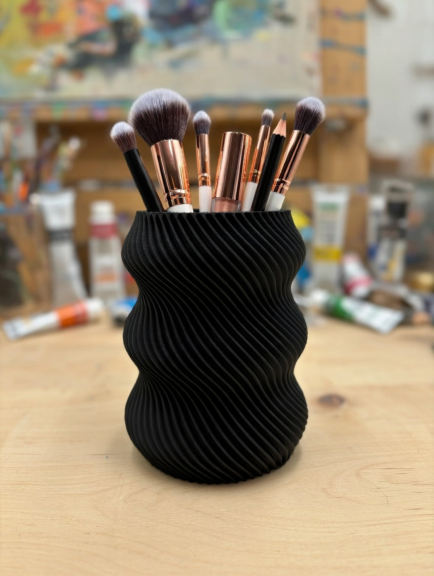 Black wavy twisted pencil holder on a marble table with books