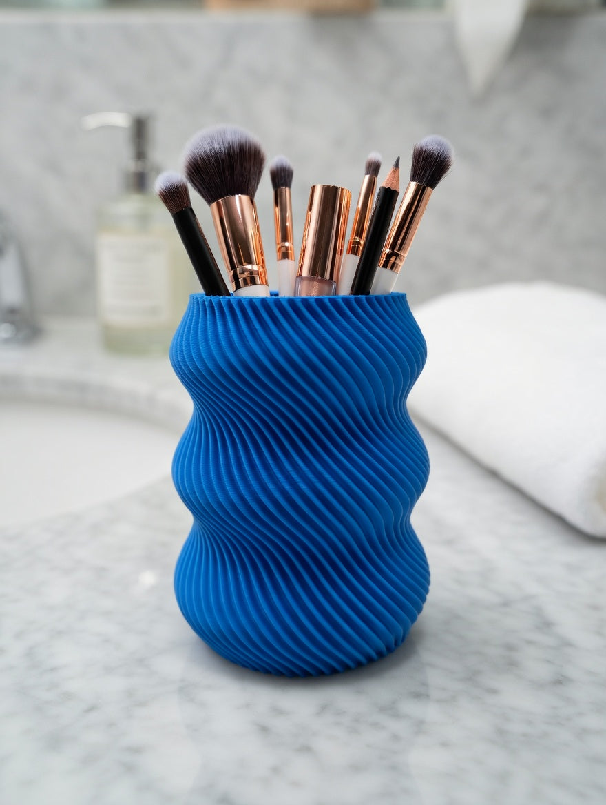 Bright blue wavy twisted pencil holder on a wooden desk with plants